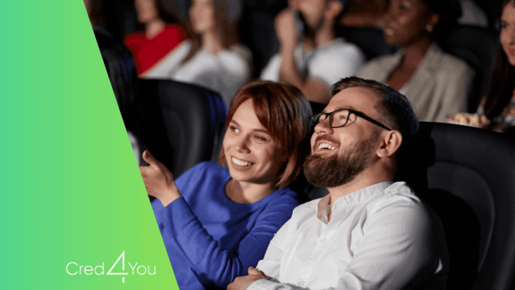 Casal sorridente assistindo a filme no cinema, representando a experiência e vantagens do Cinemark Club, com logotipo Cred4You à esquerda.