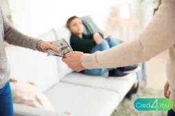 Pessoa entregando dinheiro como pagamento de pensão alimentícia, com criança ao fundo.