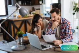 Casal reunido na mesa analisando contas e documentos no notebook, simbolizando como dividir as contas do casal de forma justa.