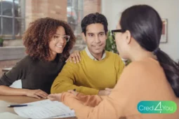Casal sorridente conversando com consultora financeira sobre empréstimo pessoal para ajudar a dividir as contas do casal.