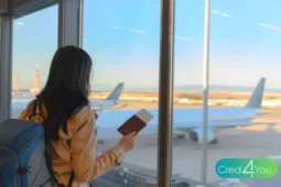 Jovem com mochila e passaporte em mãos olhando aviões no aeroporto antes de embarcar para um intercâmbio.