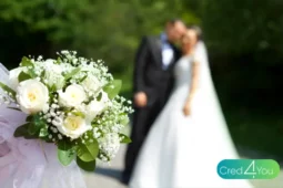 Casal de noivos ao fundo e buquê em destaque, simbolizando a união e a importância de escolher regimes de casamento adequados.
