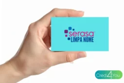 Mão segurando um cartão azul com o logotipo do Serasa Limpa Nome, representando a possibilidade de renegociar dívidas e limpar o nome no mercado.