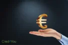 Ausgestreckte Hand mit einem schwebenden goldenen Euro-Symbol vor dunklem Hintergrund, Konzept zum Digitaler Euro.