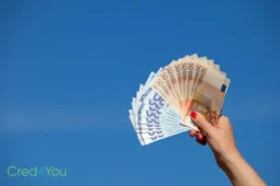 Hand mit Euro-Scheinen vor blauem Himmel, Symbol für Steuerklasse in Deutschland und deren Einfluss aufs Einkommen.