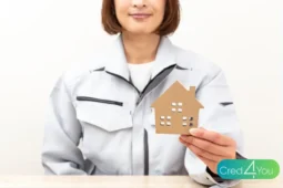 Wohngebäudeversicherung, Fachkraft hält ein Hausmodell in der Hand.