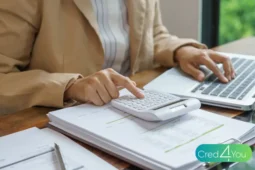 Person benutzt einen Taschenrechner auf Finanzunterlagen neben einem Laptop, Bild zum Thema dispo.