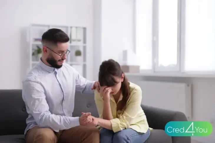 Vollstreckungsbescheid, Mann tröstet Frau, die verzweifelt auf dem Sofa sitzt, Symbolbild für Stress nach einem Bescheid.