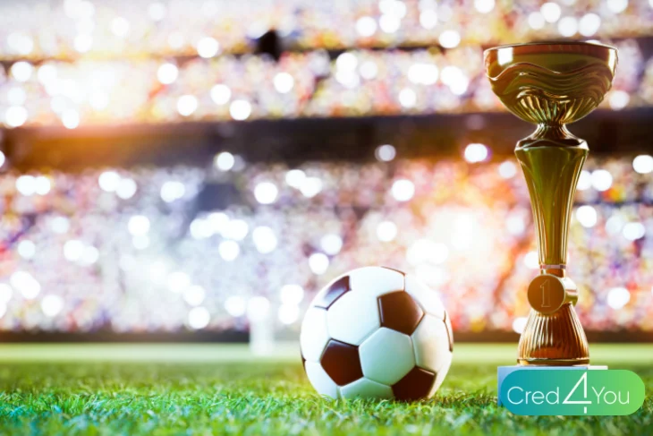 Troféu dourado e bola de futebol em campo iluminado representando a campanha Torcida BB ligada à Copa do Mundo FIFA 2026™